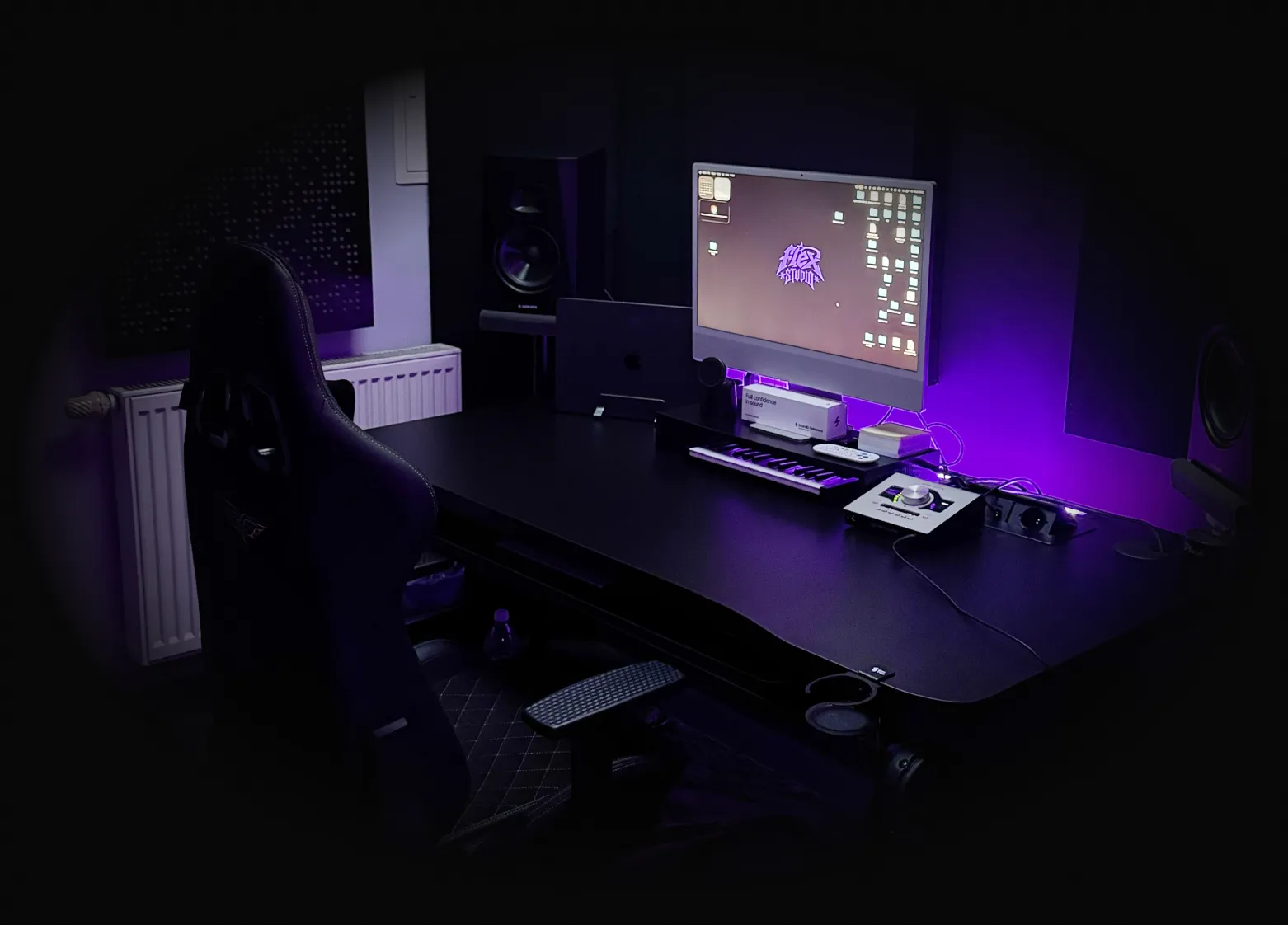 Stanowisko realizatora w FLEX STUDIO - biurko z monitorem, klawiaturą MIDI, interfejsem audio i monitorami odsłuchowymi, ściany wyłożone panelami akustycznymi.